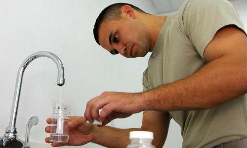 Airman pouring water into bottle for testing
